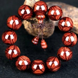 Bracelet mala en perles de bois de rose poli, grosses perles brun rouge profond avec veinage marqué et nœud décoratif. Premium rosewood mala bracelet with polished beads, deep reddish-brown grain and decorative knot.