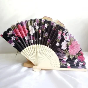 Chinese silk folding fan, black background with crimson red and rose pink peonies, white blossoms and purple lavender accents, scalloped border bamboo
