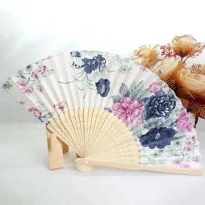 Chinese silk folding fan, white background with large indigo blue ink-style peonies and pink cherry blossom accents, bamboo ribs