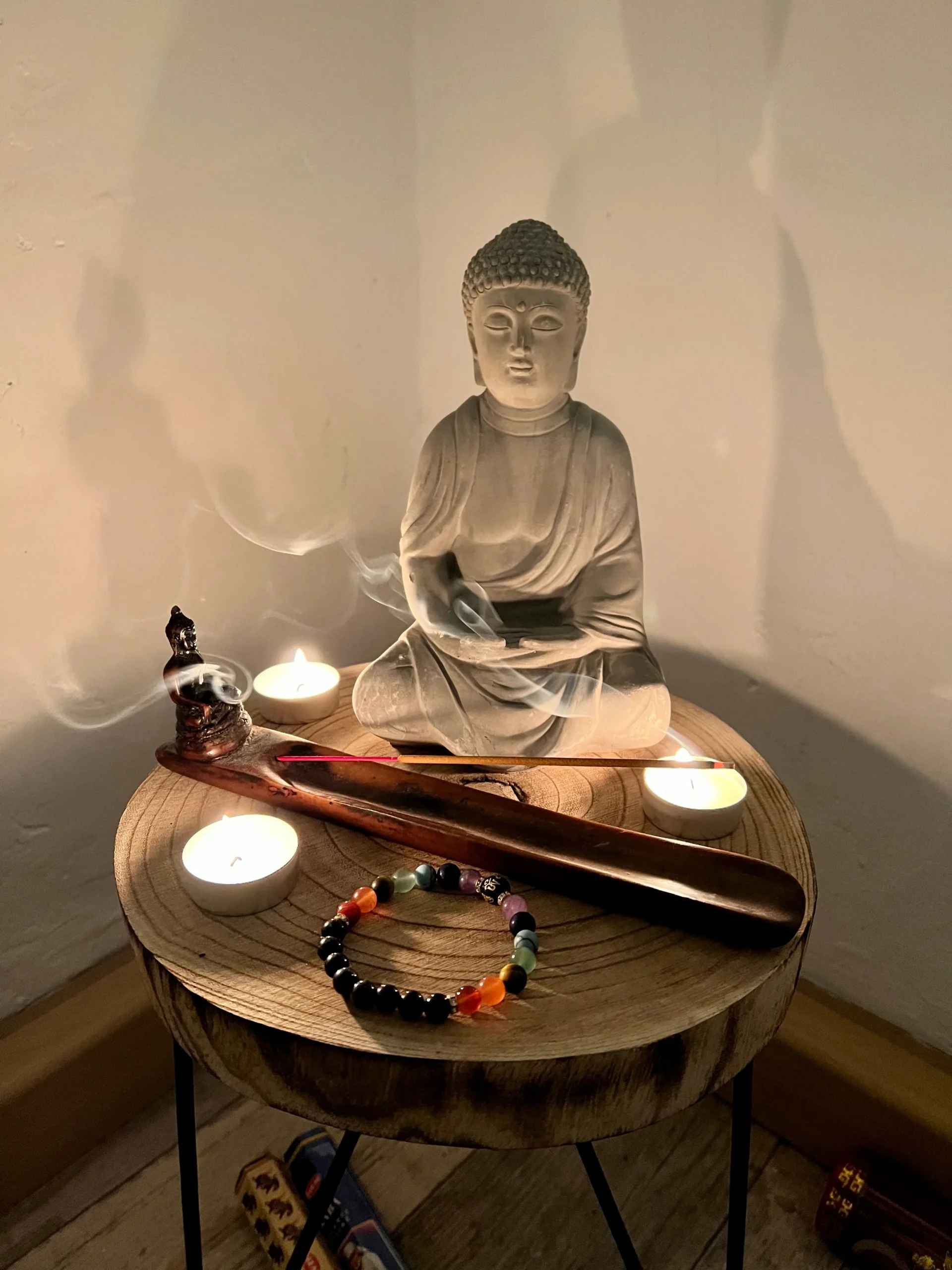 Buddhist altar with gilded statue, flowers, and candlelight — devotional home setup