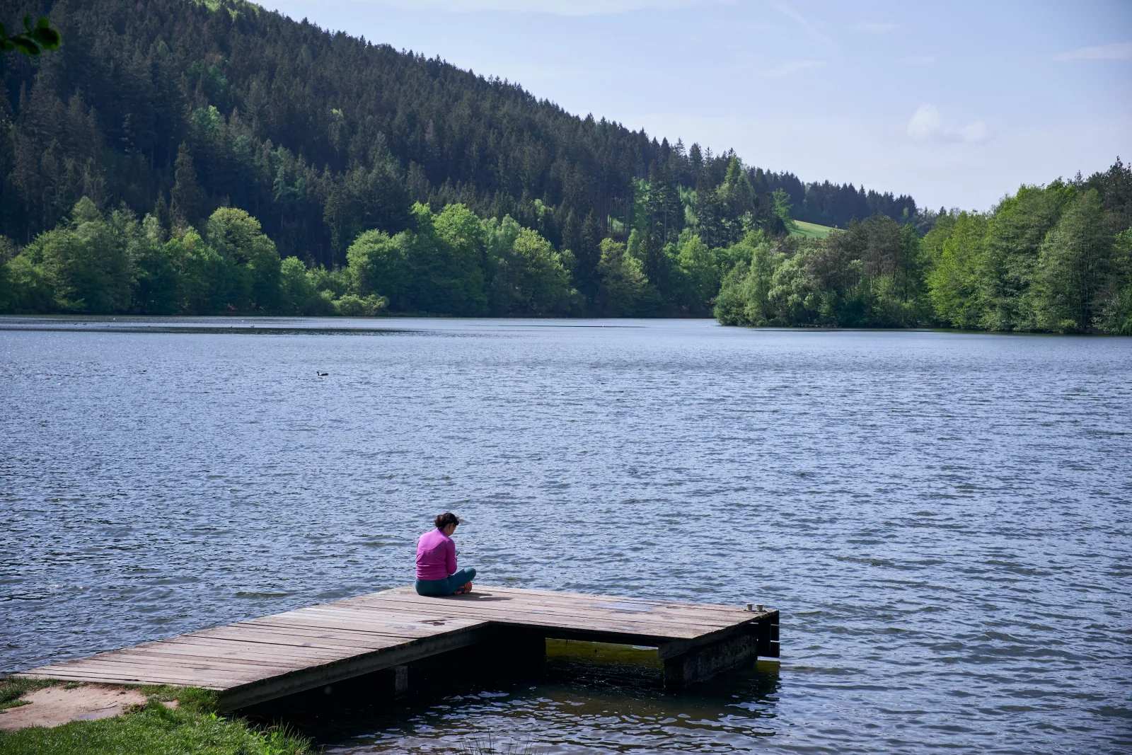 Meditator seated by a still lake at sunrise — reflection and stillness practice