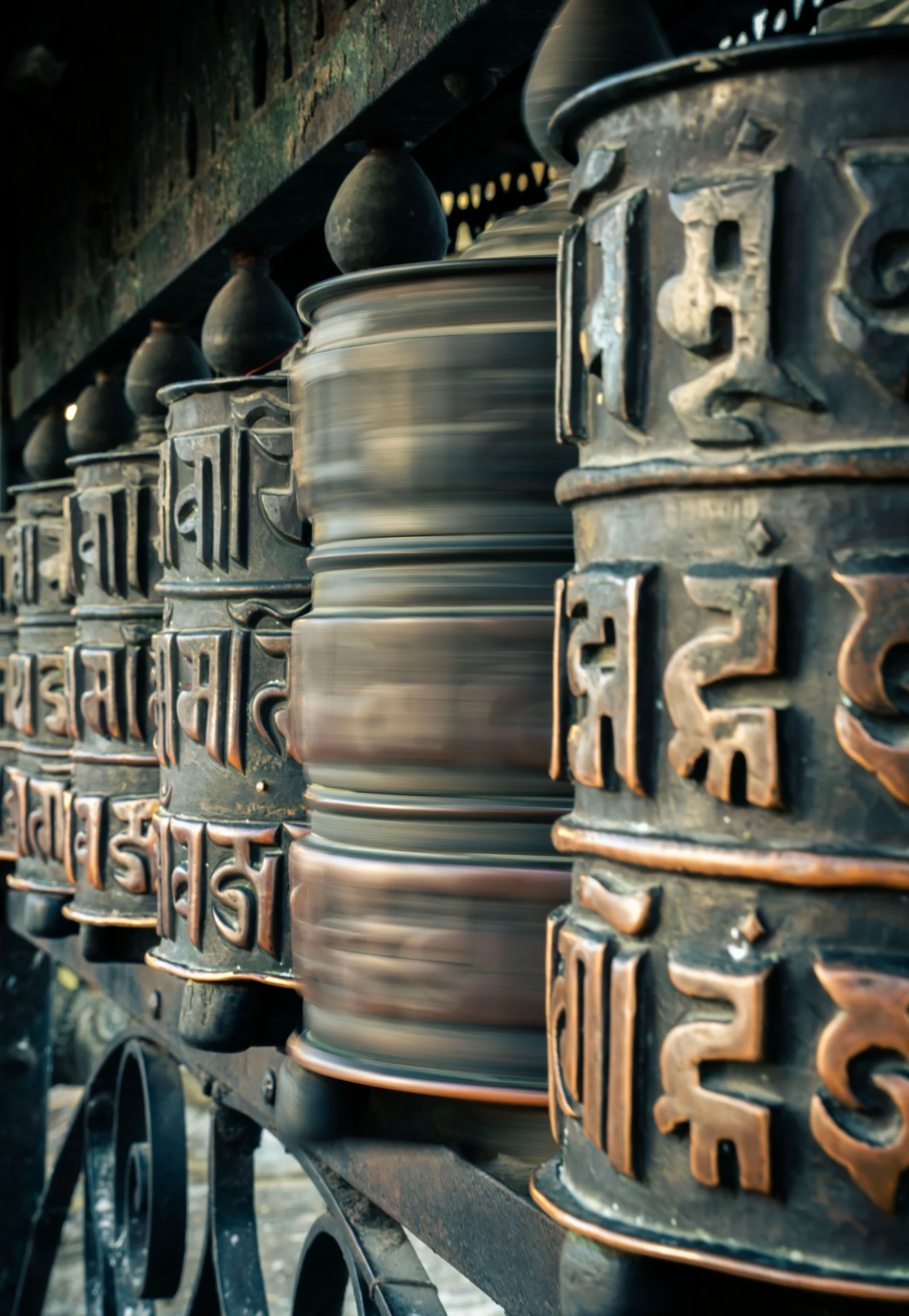 Row of Tibetan prayer wheels in metal at a Buddhist temple, Tibet