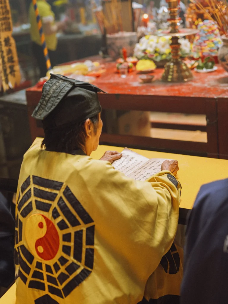 Fidele en priere devant un temple taoiste orne du symbole Ba Gua, huit trigrammes