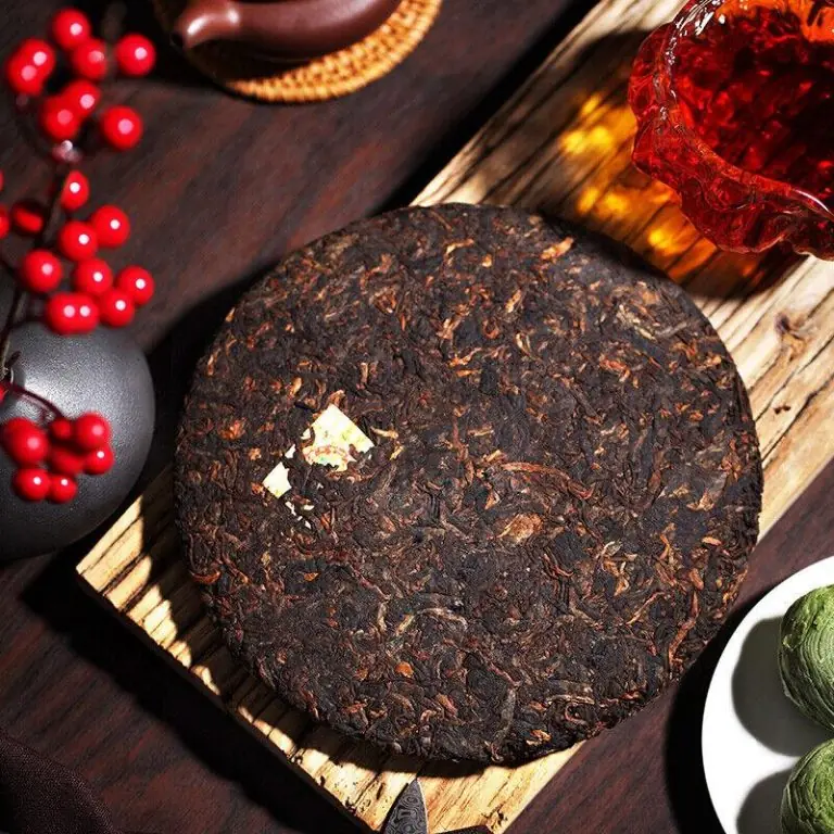 Galette de pu-erh vieillie photographiee en ambiance, theiere et liqueur rouge