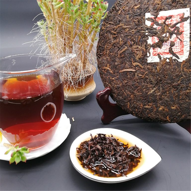 Galette de pu-erh, theiere en verre, tasse de liqueur rouge et plante succulente