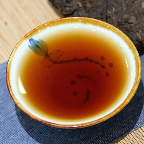 Tasse de the peinte a la main devant une galette de pu-erh